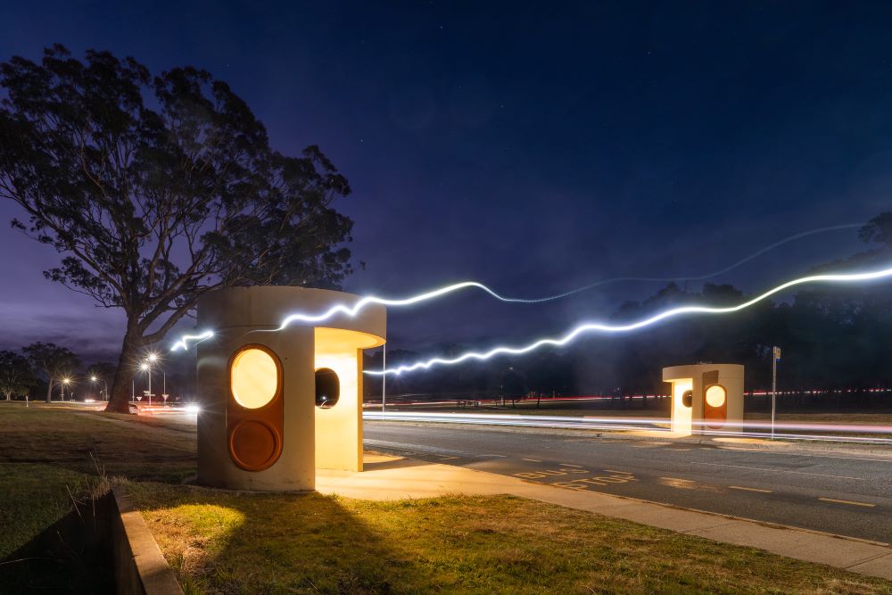 A Canberra bus stop at night time with rays of light running along the road.