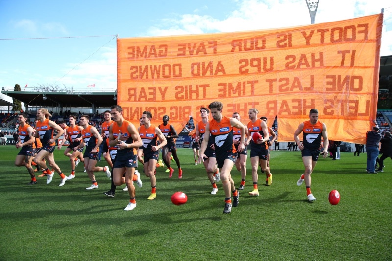 Giants football team running through a large orange banner.