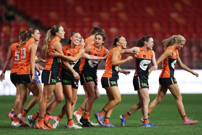 The team of AFLW Giants laughing and walking together on the field.