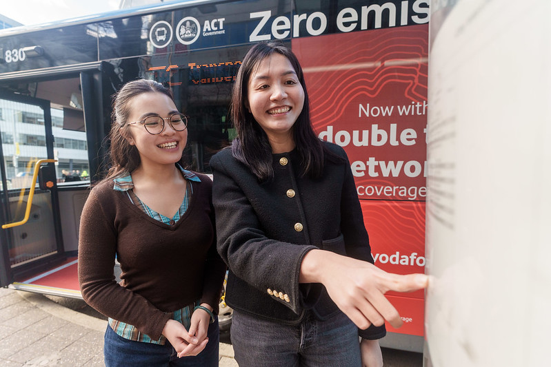 Two women stand in front of a ticket machine.