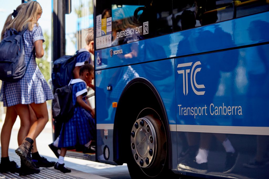 Students boarding a Transport Canberra bus at a bus stop.
